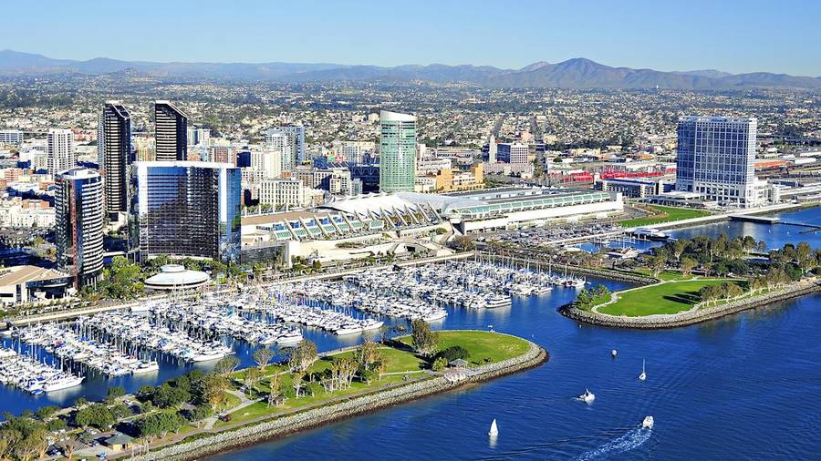 Aerial view of the San Diego bayfront, its marina full of sailboats and the downtown skyline behind.